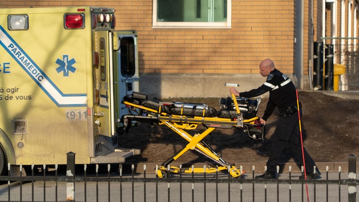 Un ambulancier rentre une civière dans une ambulance.