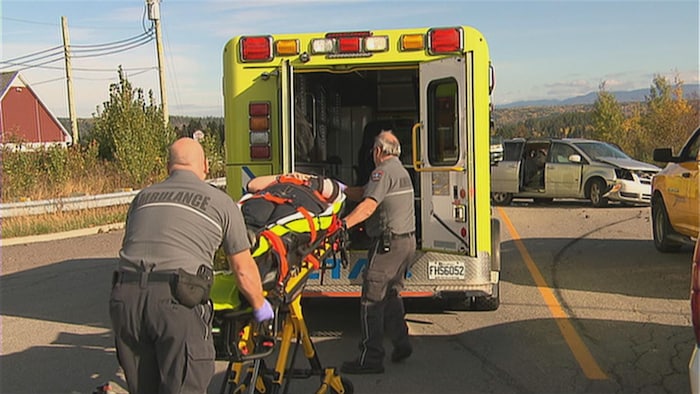 Deux paramédics transportent une civière dans l'ambulance.