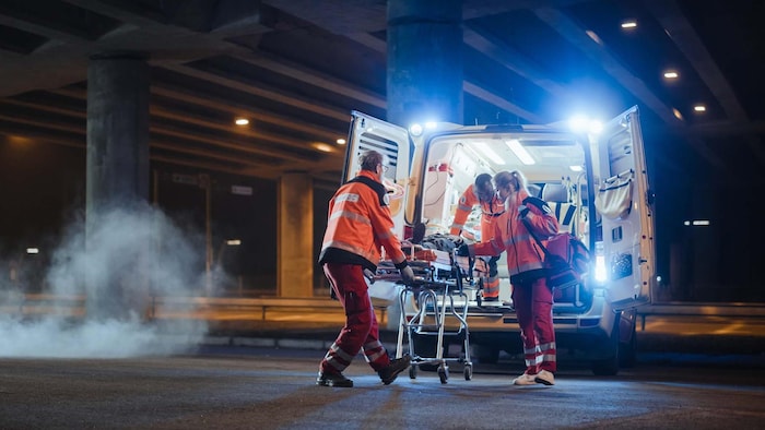 Des ambulanciers devant la porte arrière d'une ambulance.