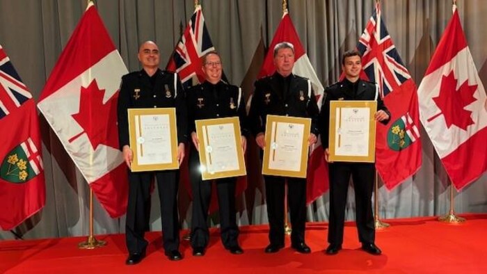 Les quatre ambulanciers paramédicaux tiennent chacun un tableau montrant leur Médaille de la bravoure.