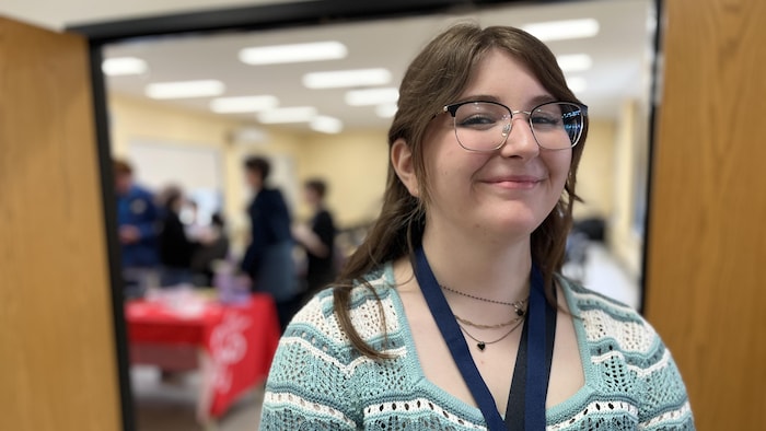 Une jeune élève en portrait, devant une classe.