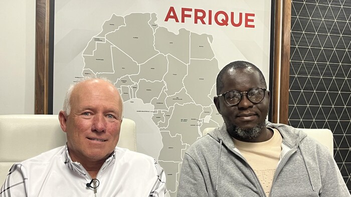 Deux hommes posent devant une carte de l'Afrique.