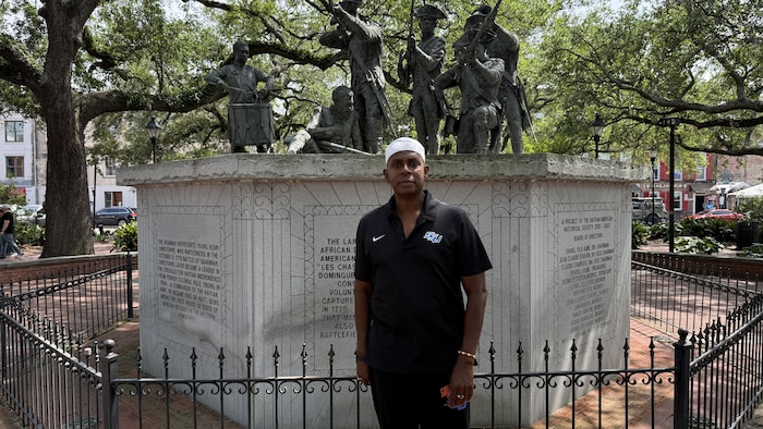 Un historien debout devant le monument des Chasseurs volontaires de Saint-Domingue.