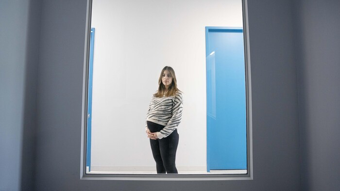 Une femme enceinte derrière une vitre.