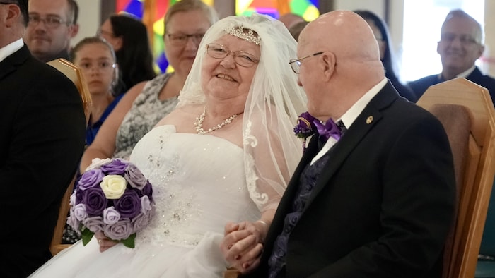 Deux nouveaux mariés, âgés, qui sourient.