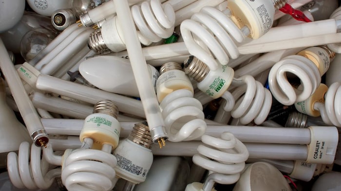 Un mélange d'ampoules électriques usagées qui s'empilent dans une boîte.