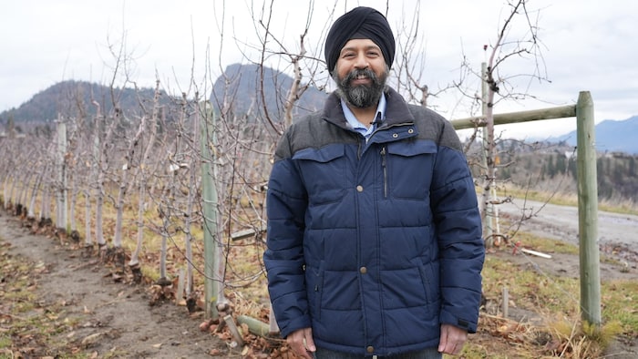 Amritpal Singh devant des pommiers dénudés, à Summerland le 12 décembre 2025.