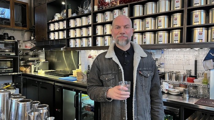Un homme tient une verre près d'un bar.