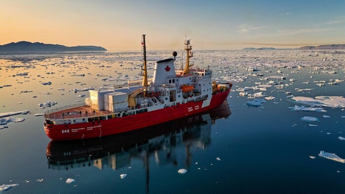Une navire entouré de plaques de glace sur un cours d'eau. 