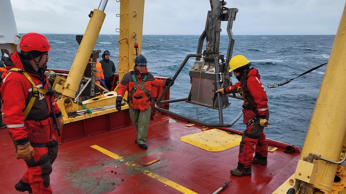 Des chercheurs installent un appareil utilisé pour de l'échantillonnage marin à bord d'un navire canadien de recherche, en octobre 2024.