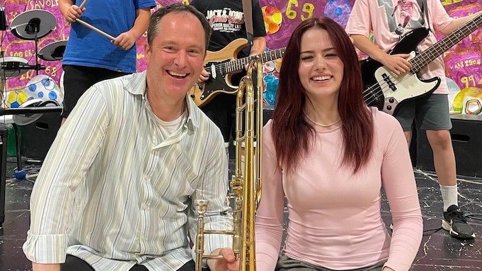 Jim Tranquilla et Amy Robichaud tenant un trombone, assis devant trois autres jeunes musiciens.