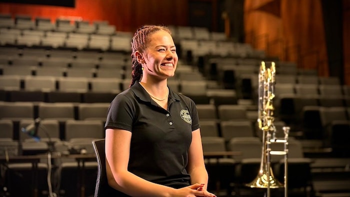 Amy Robichaud, souriant à coté de son trombone.