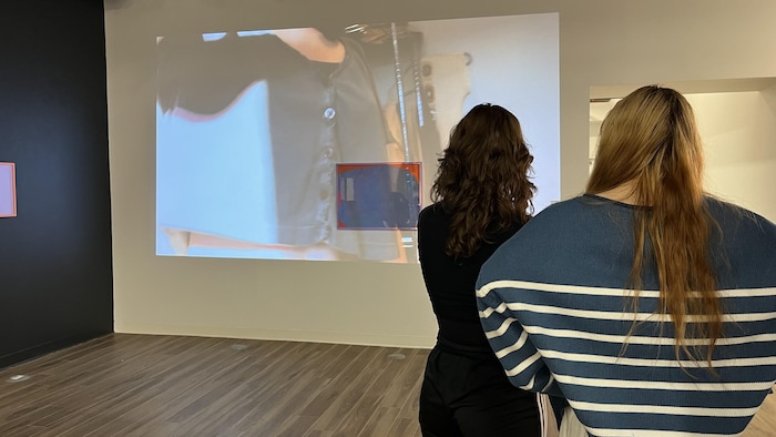 Deux personnes regardent une vidéo sur un mur. 