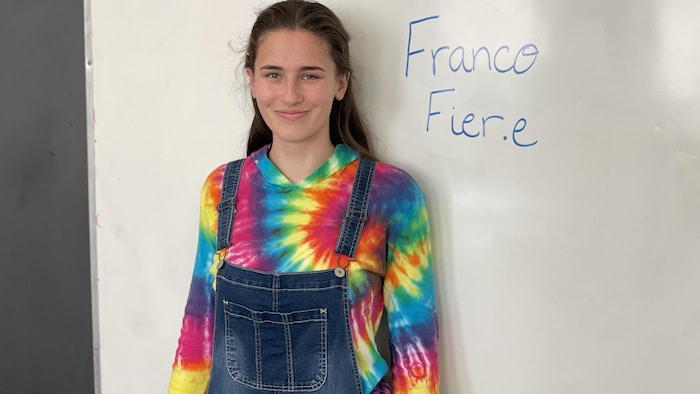 Anastasia est debout à côté d'un tableau où il est écrit : franco fière.