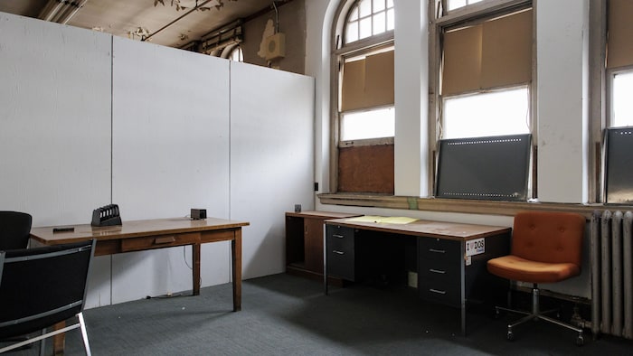 Un ancien bureau en mauvais état dans l'ancien hôtel de ville de Toronto. Du carton est posé sur les fenêtres.