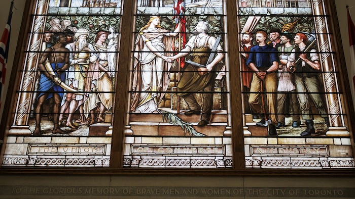 Un vitrail montrant des personnages des deux côtés d'une femme tenant un drapeau du Royaume-Uni. 