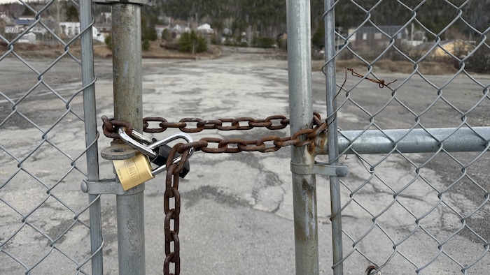 Terrain vacant avec une clôture et un cadenas au centre-ville de Gaspé