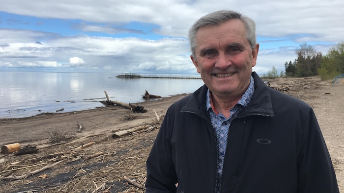 Un homme devant une plage jonchée de déchets.