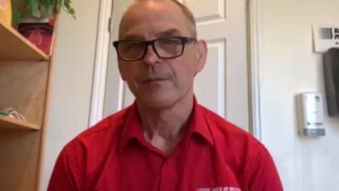 André Riopel porte des lunettes et une chemise rouge.