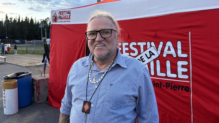 Le maire, dans sa chemise à carreaux, pose devant la tente rouge du Festival de la famille.