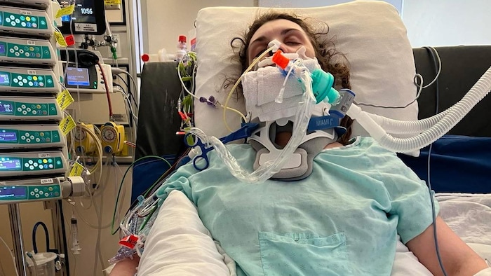Une femme alitée. Elle est branchée à divers appareils médicaux.