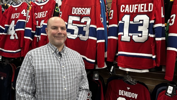 Un homme devant un étalage de gilets de hockey.
