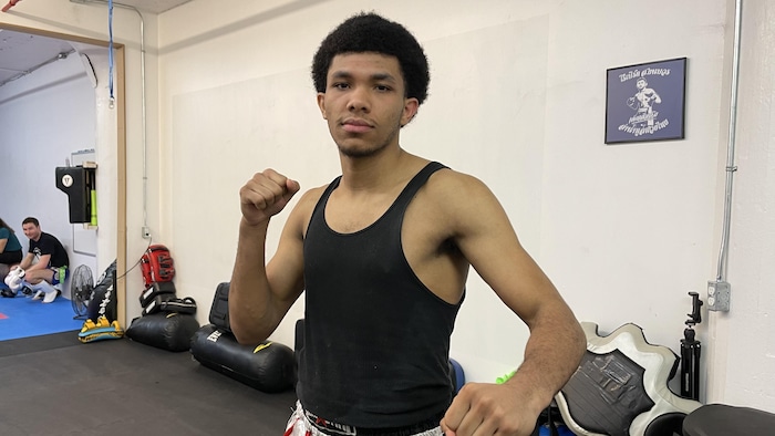 Andrews Pimparé-Édouard pratique le muay thaï à l'école Yeuang Kraai à Montréal. Il est debout montrant ses poings. 