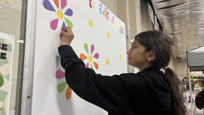 Angélie Bélanger colle un message de positivité sur le tableau d'Aire ouverte.