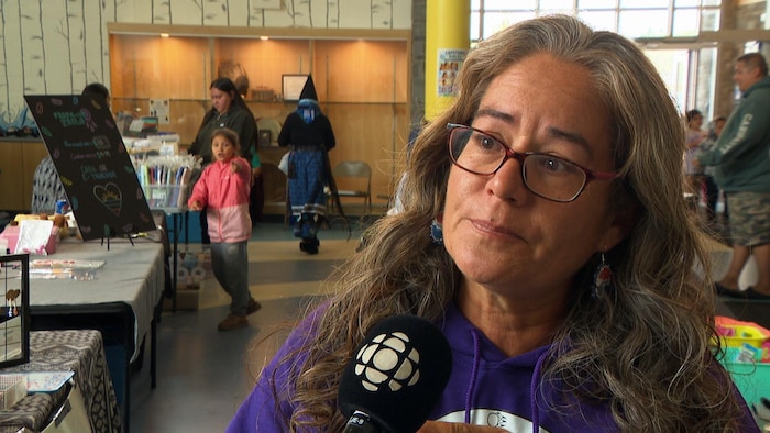 Angeline Purcell interviewée au milieu d'une petite foule dans un centre communautaire.