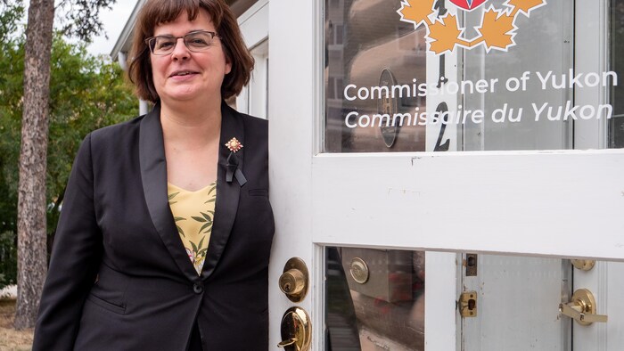 Angélique Bernard, commissaire du Yukon, se tient devant une porte sur laquelle est inscrit son nom.