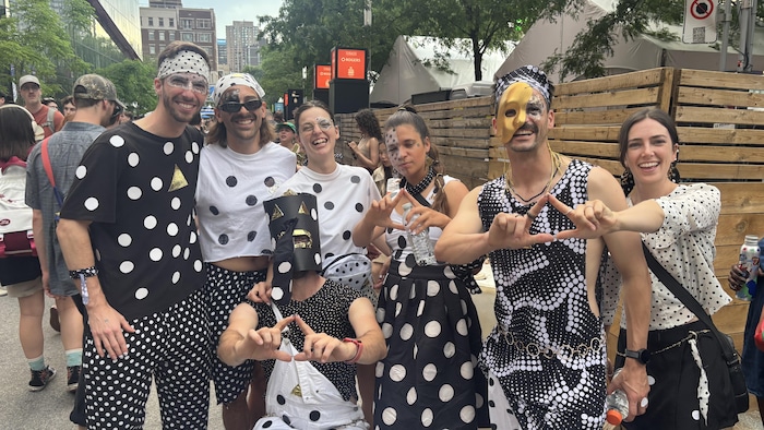 Des personnes vêtues de vêtements à pois sourient à la caméra. 