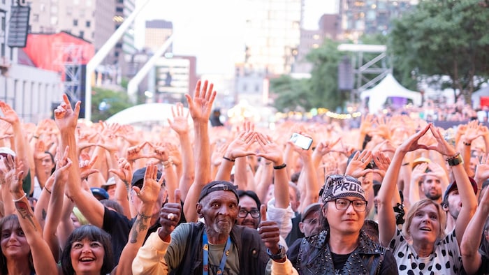 Des milliers de personnes lèvent les mains dans les airs. 