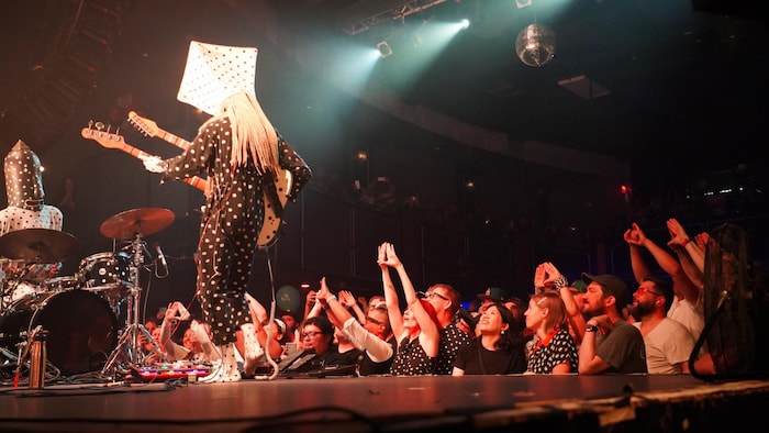 Des gens dans la foule forment le symbole du triangle lors du concert d'Angine de poitrine à Vancouver, le 23 août 2026.
