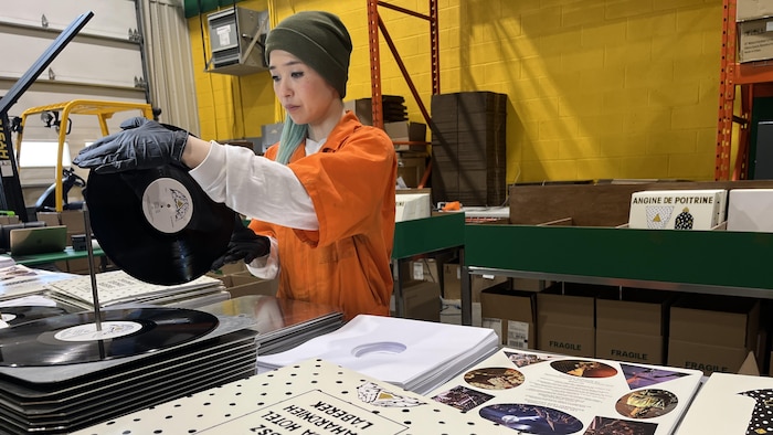 Une femme qui presse un vinyle d'Angine de Poitrine