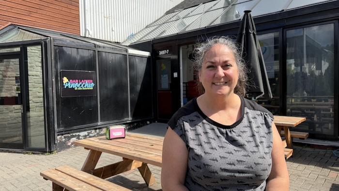 Anick Arsenault regarde l'objectif en souriant. Elle est devant son commerce.