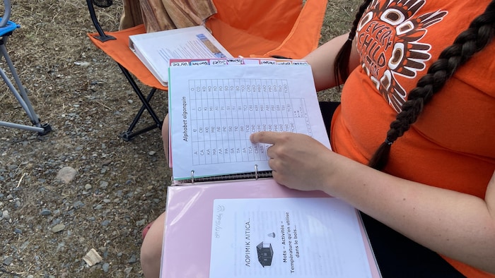 Marie-Soleil Mapachee pointe l'alphabet algonquin dans un cartable.