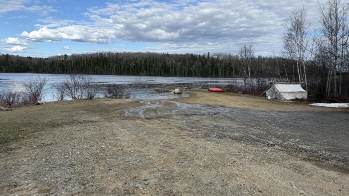 Un canot et une tente reposent sur la rive de la rivière Harricana.