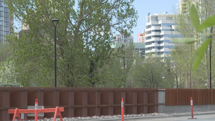 Une barrière anti-inondation longe une route à Calgary, avec des immeubles visibles à l’arrière-plan.