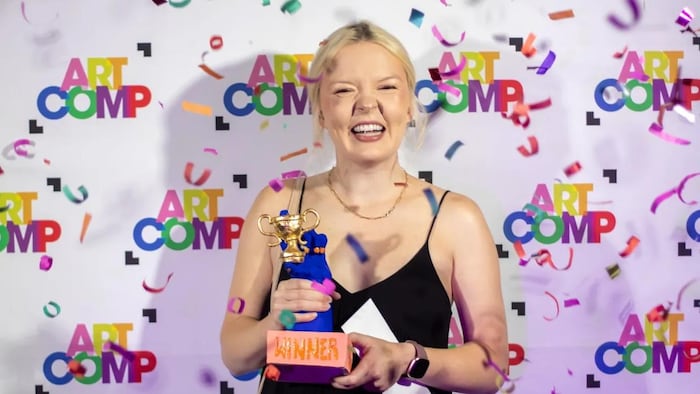 Anna Wilson rit en tenant son trophée alors que des confettis colorés tombent autour d’elle.
