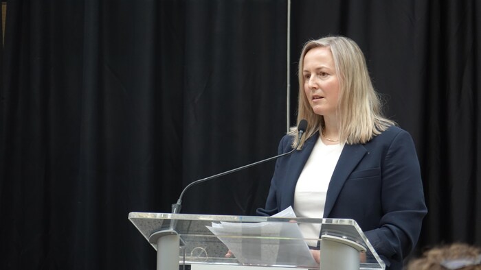 Annalee Coakley est debout devant un lutrin.