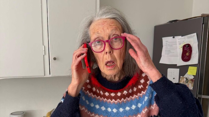 L'autrice a l'air ébahi au téléphone, dans sa cuisine. 