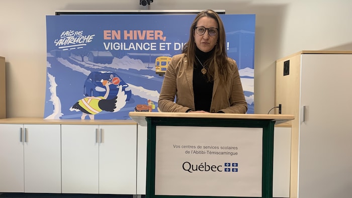 Une femme debout parle derrière un pupitre.
