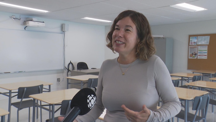 Une femme dans une classe parle au micro.