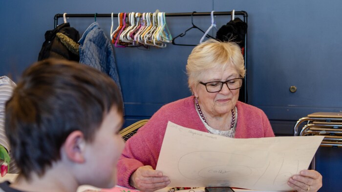 Une femme lit un document, assise à côté d'enfants.