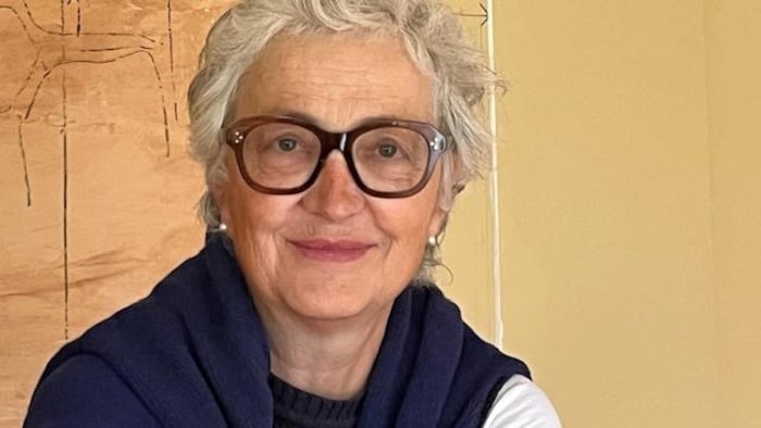 Anne Worrall pose devant une oeuvre d'art.