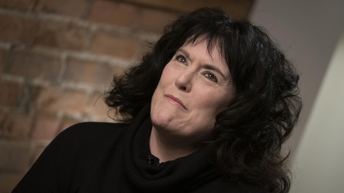 Annick Charette serre les lèvres en regardant au loin pendant une entrevue.