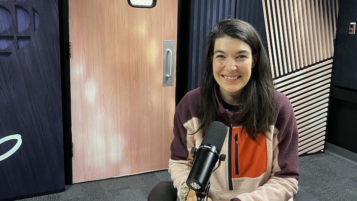 une femme en studio radio sourit à la caméra