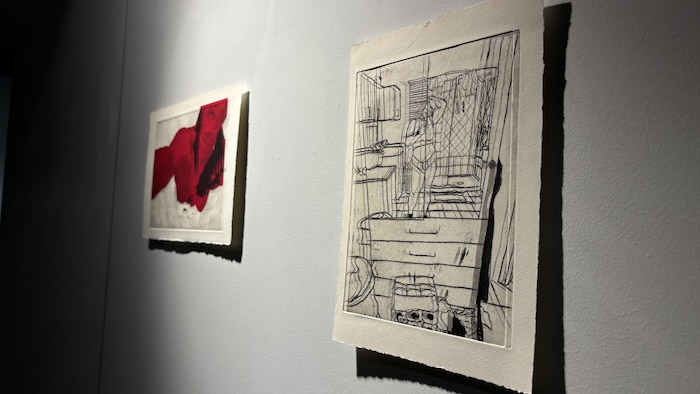 Un gros plan pris en angle de deux œuvres encadrées accrochées côte à côte sur un mur de galerie.