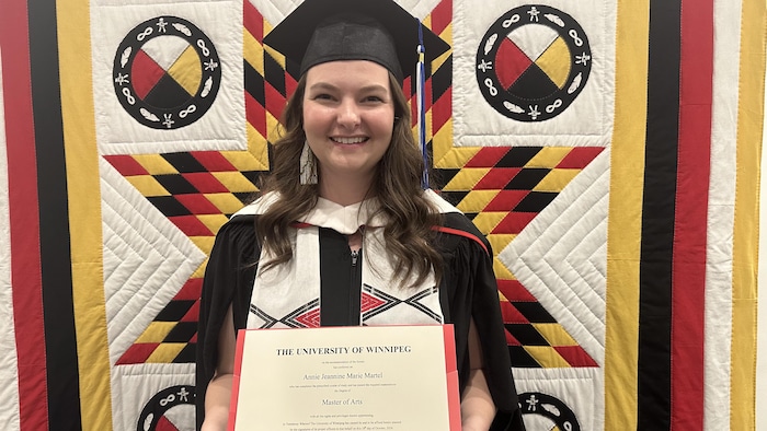 Annie Martel en robe de graduation tentant son diplôme.