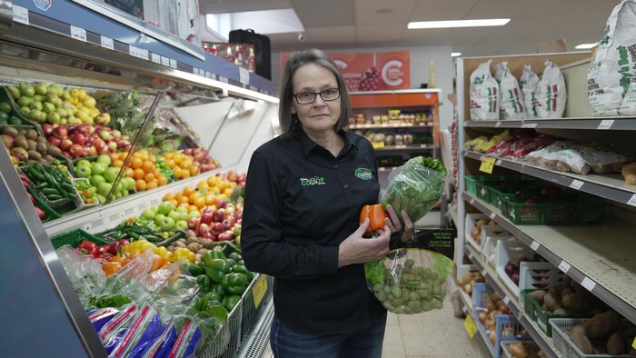 Une femme avec des fruits et légumes dans les mains.